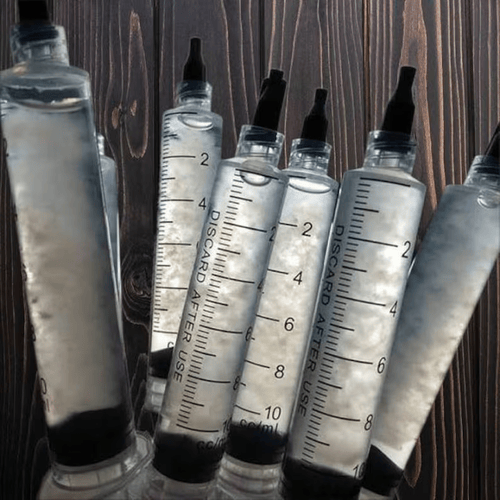 Set of syringes with measurement markings on a wooden background